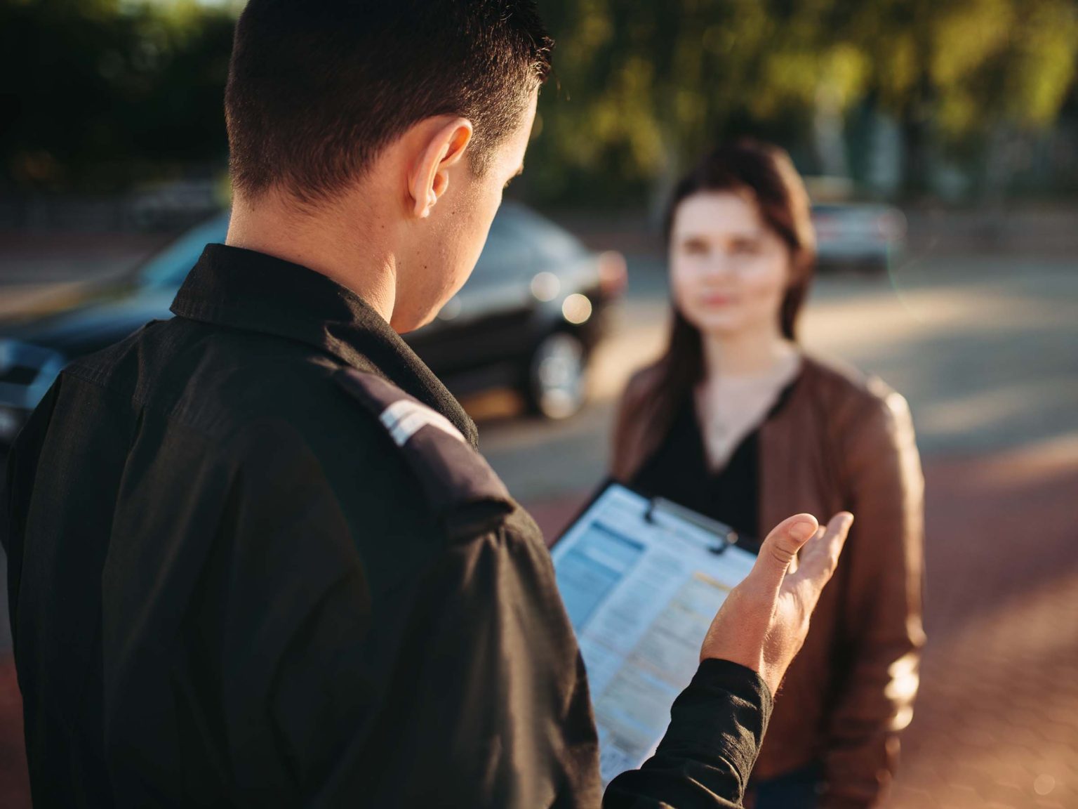 A photograph of a police officer reading the law to a female driver during a traffic stop.